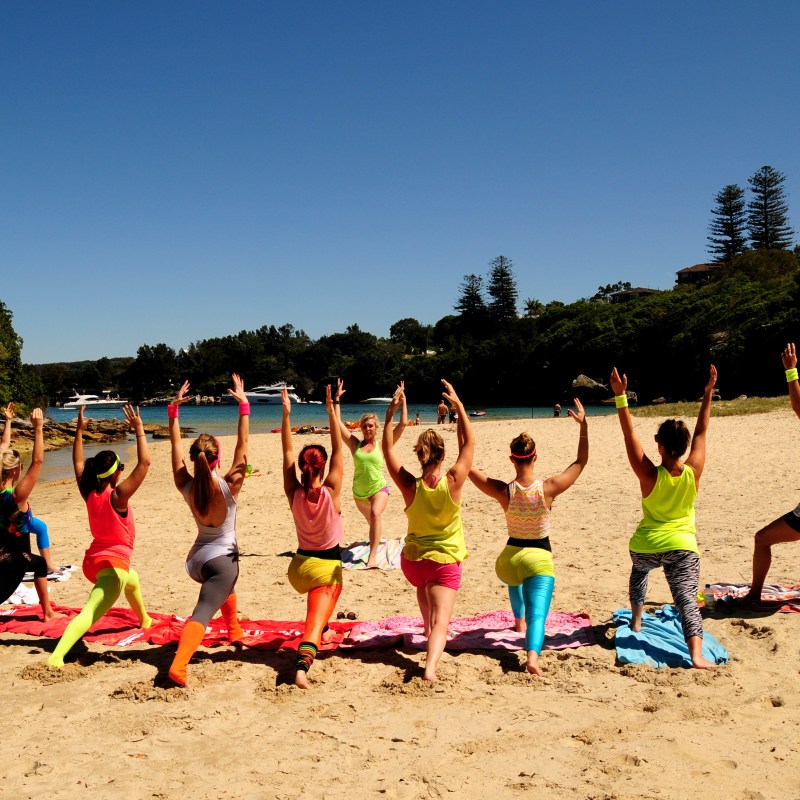 Group of girls doing beach yoga